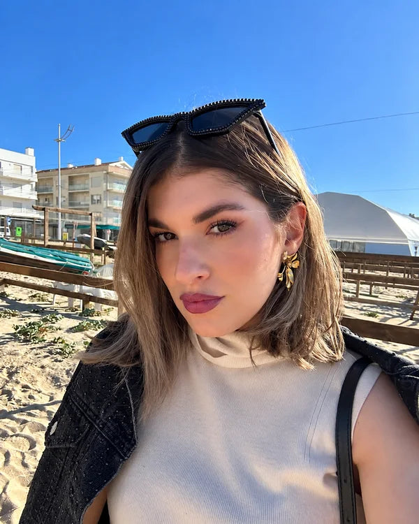 Kvinde med solbriller i håret på en strandpromenade