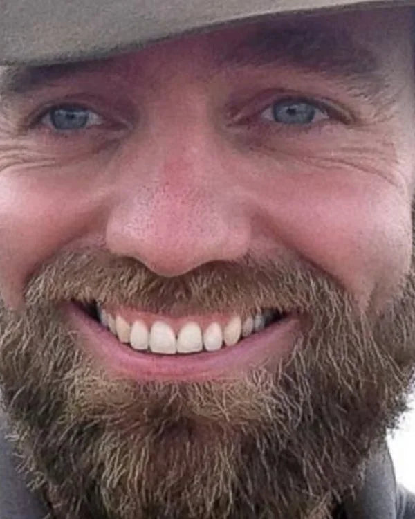 Smilende mand med fuldskæg og hat